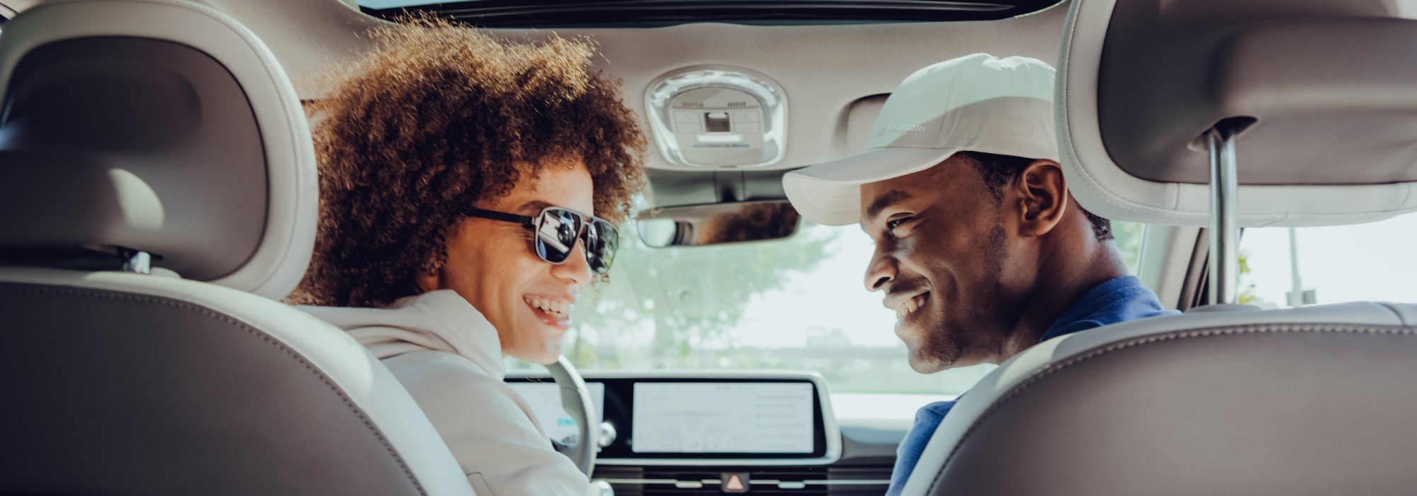 Smiling man and woman in a Hyundai car, promoting the Hyundai Collection.